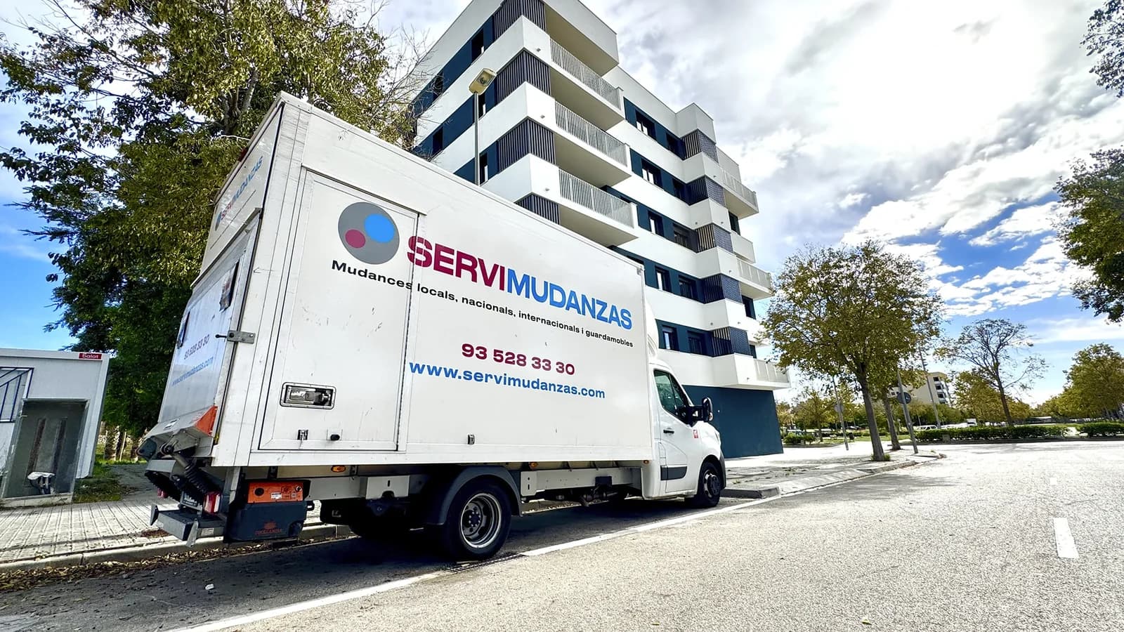 Camión Servimudanzas estacionado frente a edificio residencial moderno