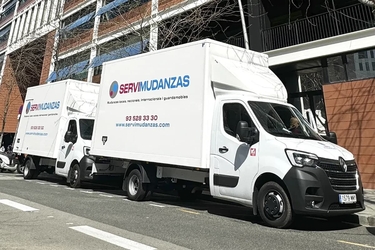 Camiones de mudanza Servimudanzas aparcados en calle del Eixample, Barcelona