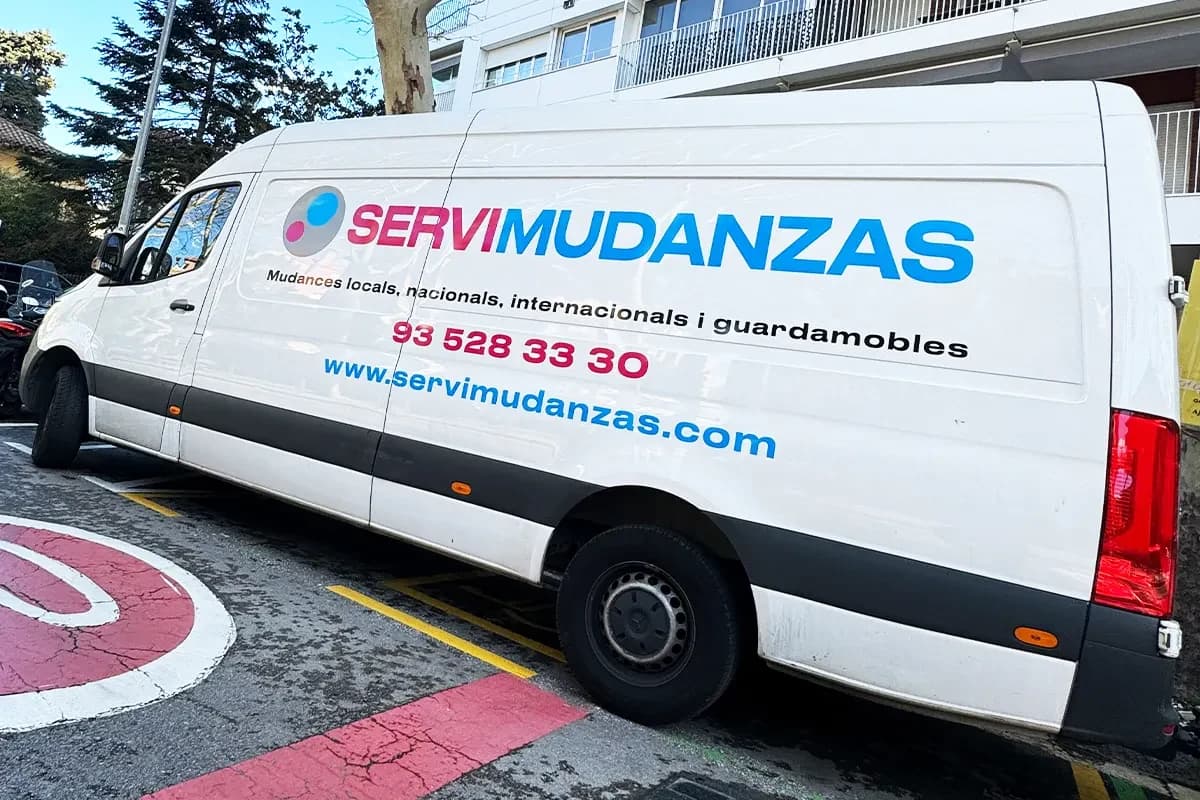 Furgoneta larga de Servimudanzas aparcada en calle de Barcelona
