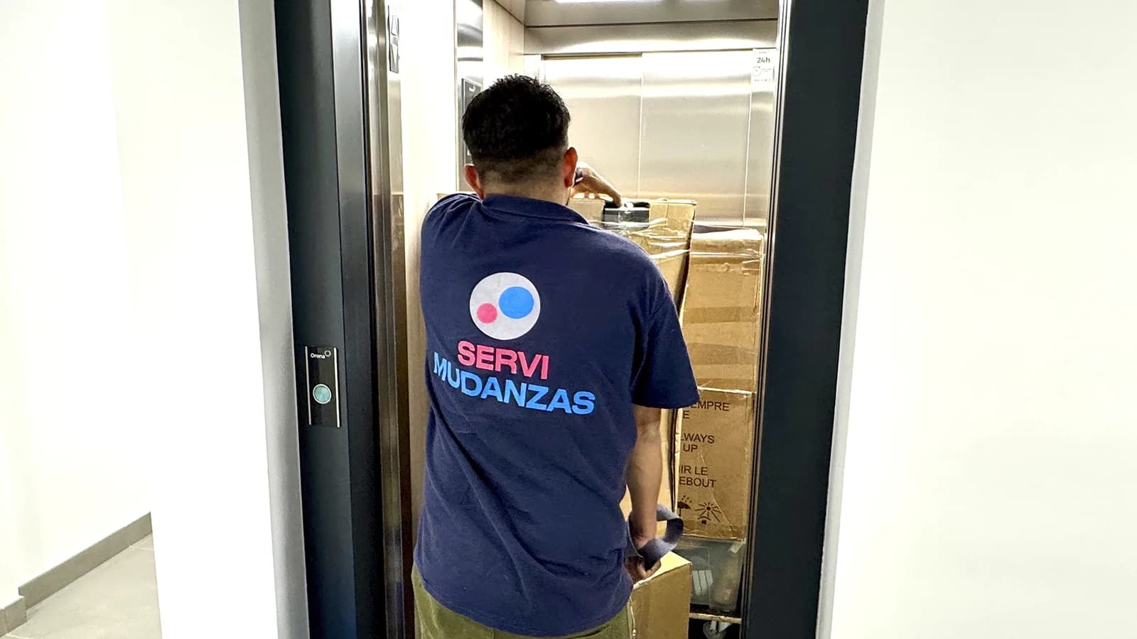 Operario de Servimudanzas en ascensor cargando cajas durante mudanza en edificio