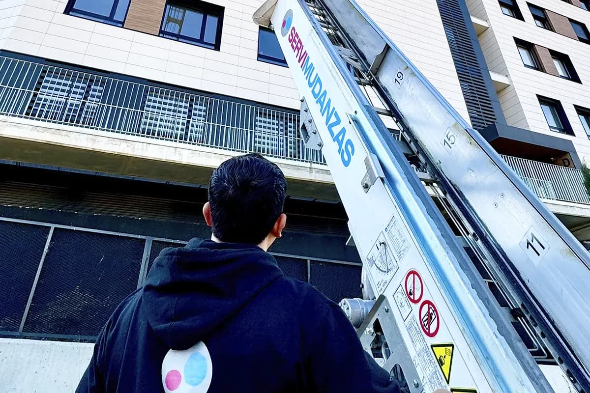 Operario de Servimudanzas supervisando descenso de elevador en edificio