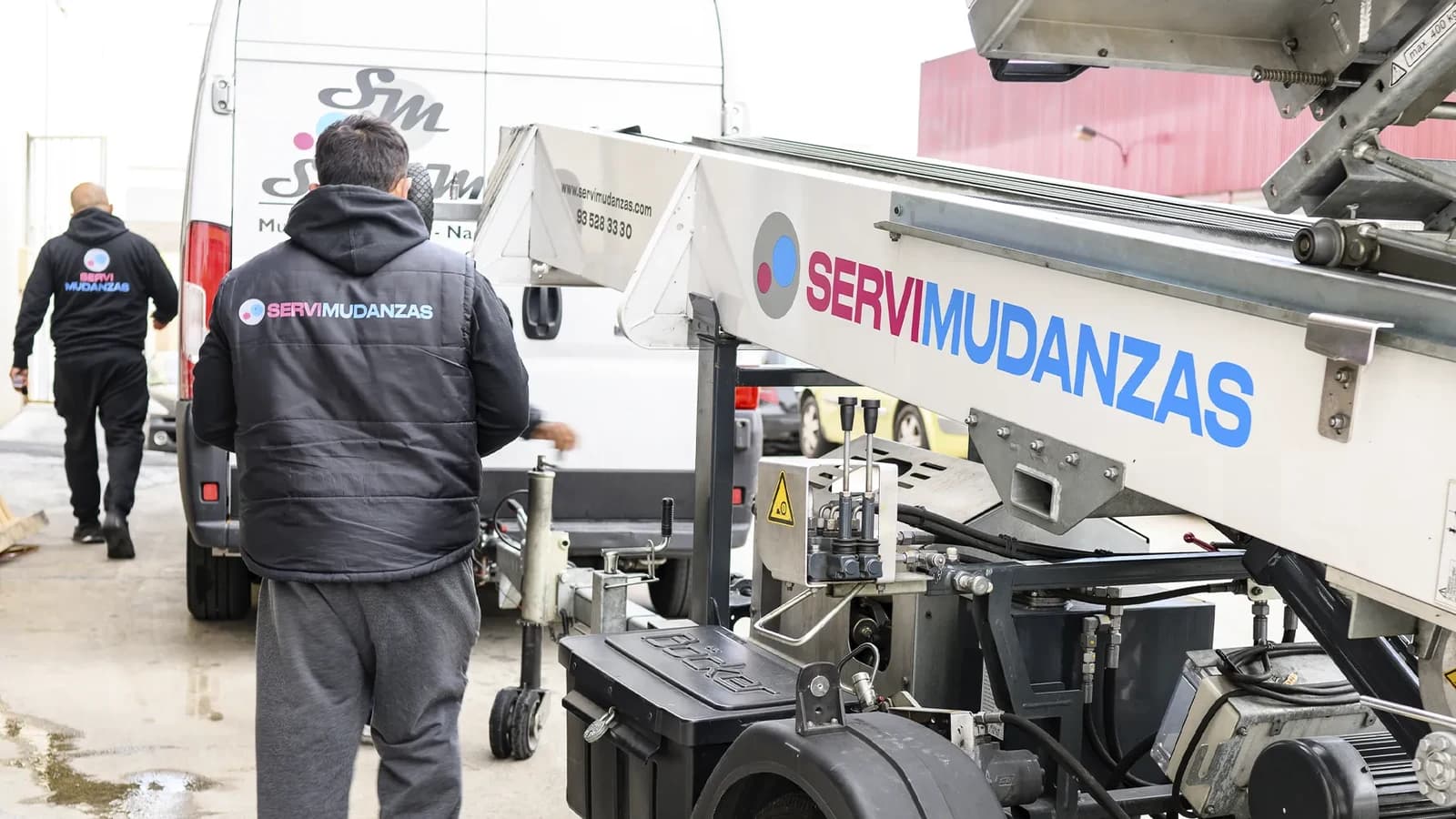 Operarios de Servimudanzas con uniforme corporativo junto a plataforma elevadora en mudanza